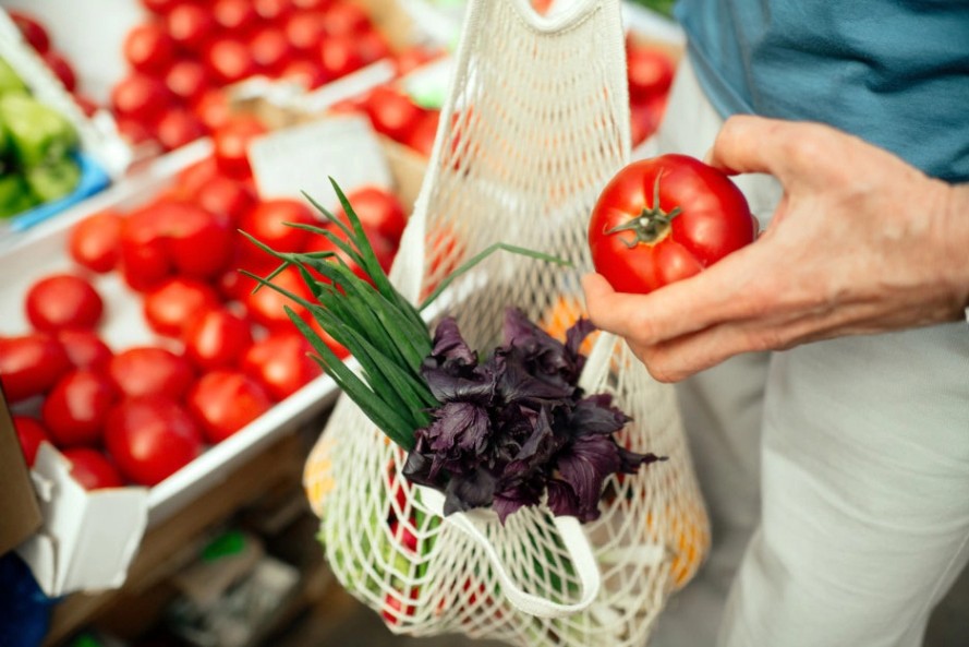 장바구니에 채소를 담고 있는 사람의 손