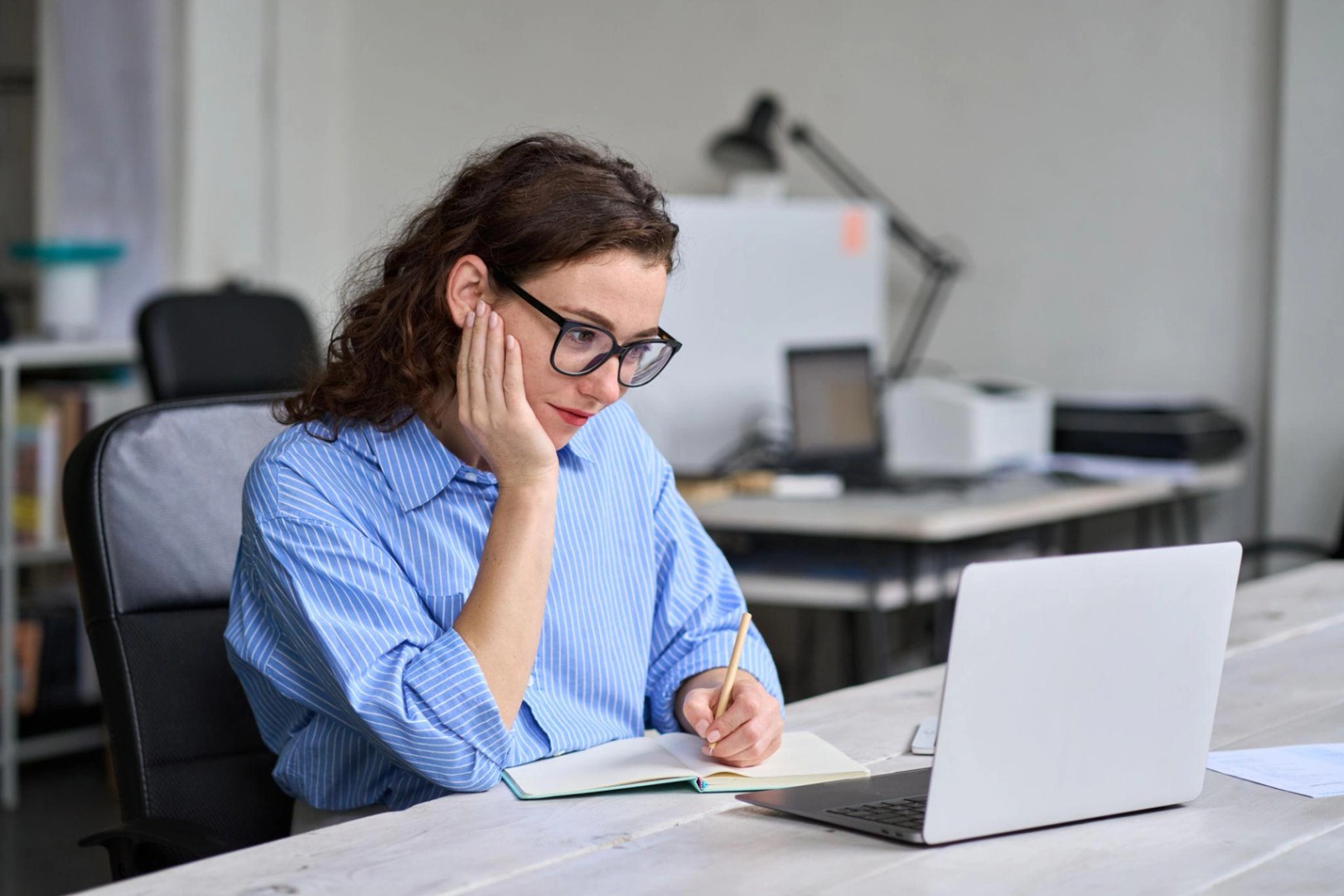 Young business woman using laptop watching online webinar at work in office.