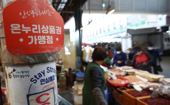 전통시장 내 온누리상품권 가맹점 안내 표지판과 시장 상인의 판매 모습