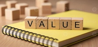 Wooden blocks spelling VALUE resting on a yellow notebook on a... spelling VALUE resting on a yellow notebook on a wooden desk...