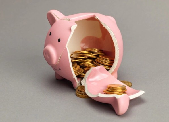 회색 배경에 동전이 있는 깨진 돼지 저금통. | 프리미엄 사진