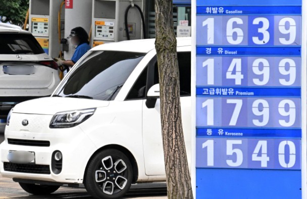 주유소에서 차량이 주유 중이며, 휘발유 1639원·경유 1499원 등의 유가가 안내된 가격 표지판이 함께 보임