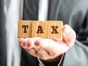 This may contain: a person holding up a wooden block with the word tax on it