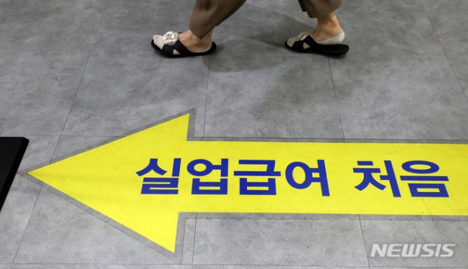 실업급여 신청을 위한 안내 표지 위를 지나가는 사람의 발