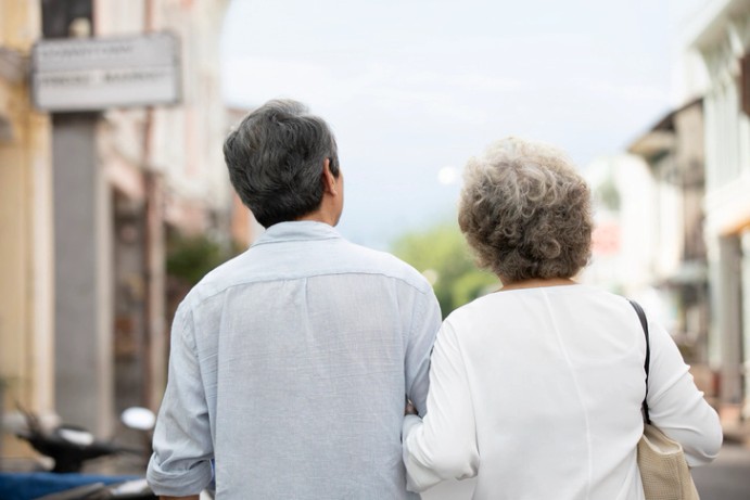 국민 연금 - 팔짱을 끼고 함께 거리를 걷는 중년 이상의 부부의 뒷모습